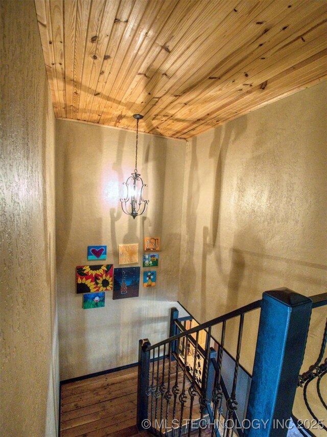 stairs featuring a chandelier, wooden ceiling, and wood finished floors