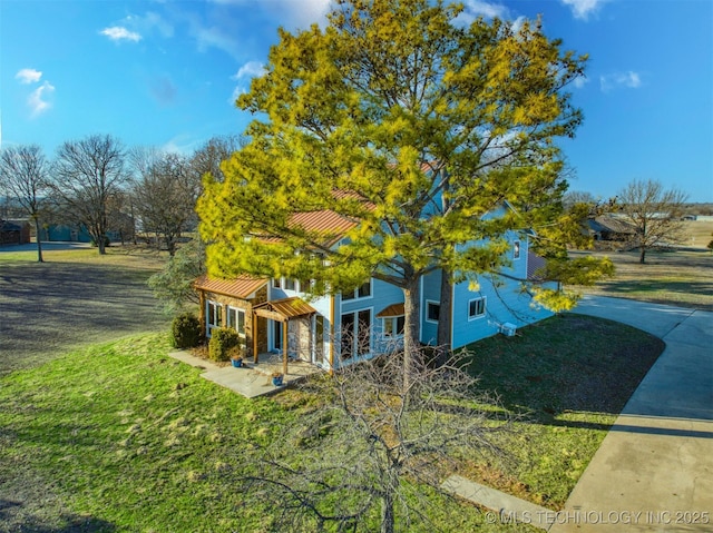 view of front of house featuring stone siding, metal roof, a front lawn, and a standing seam roof