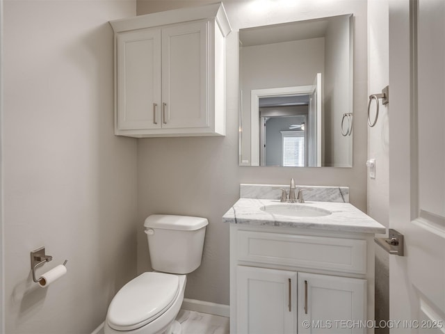 half bathroom featuring marble finish floor, vanity, toilet, and baseboards