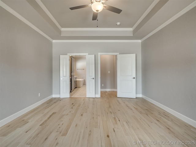 unfurnished bedroom with light wood finished floors, baseboards, a raised ceiling, and ornamental molding