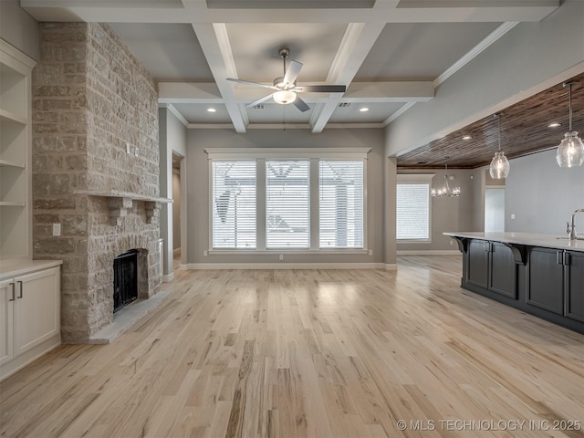 unfurnished living room featuring light wood-style floors, coffered ceiling, a fireplace, and ceiling fan