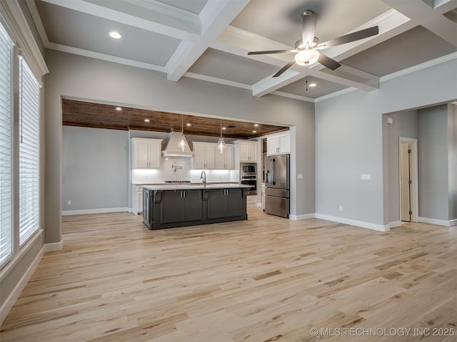 kitchen with coffered ceiling, custom range hood, stainless steel appliances, light wood-style floors, and white cabinetry