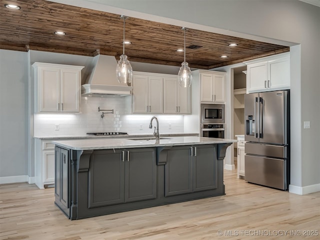 kitchen with appliances with stainless steel finishes, a sink, white cabinets, and custom range hood