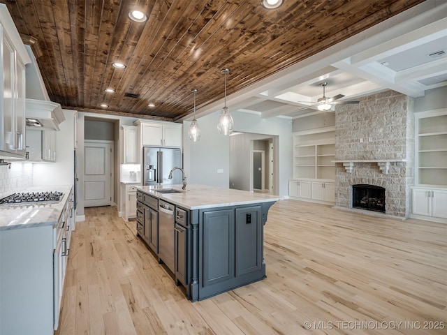 kitchen with stainless steel appliances, wood ceiling, white cabinets, a sink, and light wood-type flooring