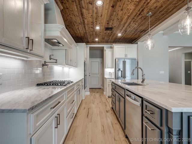 kitchen with custom exhaust hood, appliances with stainless steel finishes, white cabinets, a sink, and wooden ceiling