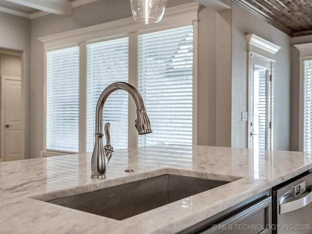 kitchen featuring light stone countertops, crown molding, a sink, and dishwasher