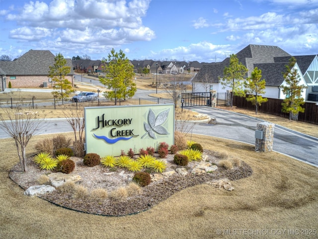 community sign featuring a gate, a residential view, and fence