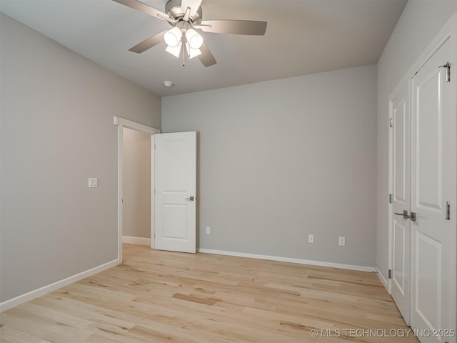 unfurnished bedroom featuring a ceiling fan, a closet, light wood-style flooring, and baseboards