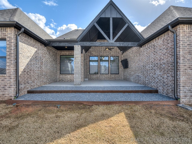 view of exterior entry with brick siding and a patio