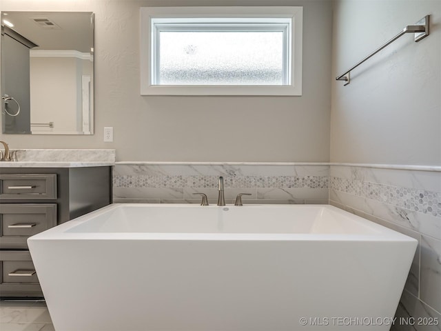 full bath with visible vents, marble finish floor, a soaking tub, and vanity