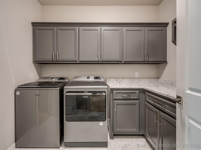 washroom featuring cabinet space, marble finish floor, and washing machine and clothes dryer