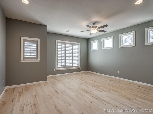 empty room featuring a ceiling fan, baseboards, visible vents, and wood finished floors