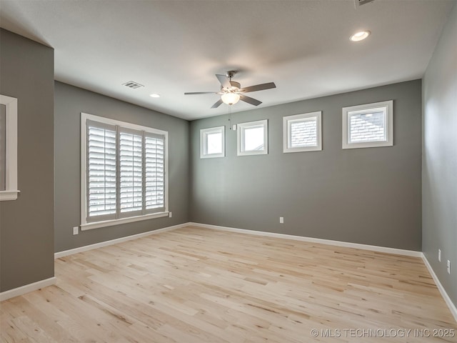 empty room featuring a ceiling fan, visible vents, baseboards, and wood finished floors