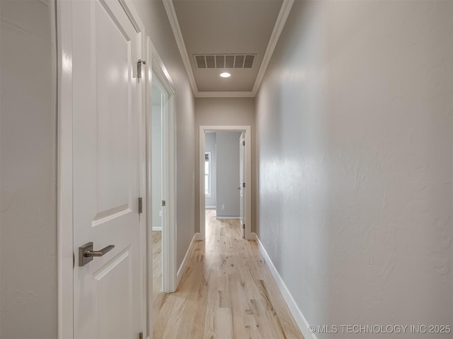 hall featuring baseboards, ornamental molding, visible vents, and light wood-style floors