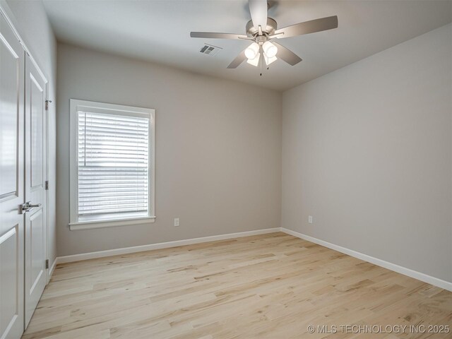 empty room with a ceiling fan, baseboards, visible vents, and wood finished floors