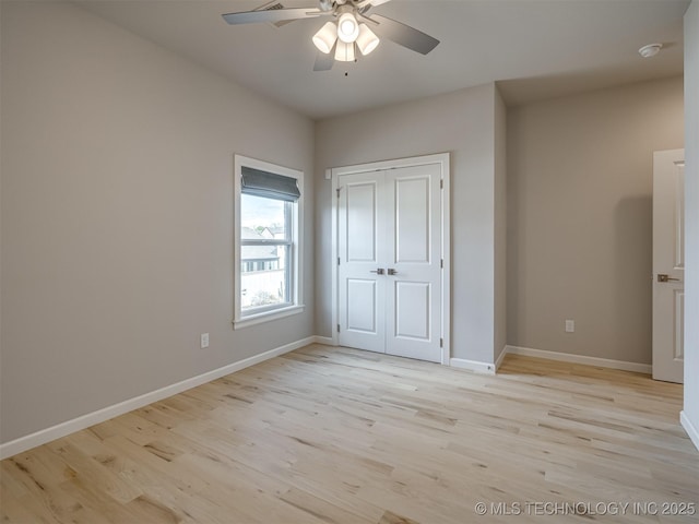 unfurnished bedroom featuring light wood-style flooring, baseboards, ceiling fan, and a closet