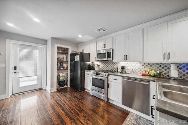 kitchen featuring visible vents, white cabinets, dark wood finished floors, stainless steel appliances, and backsplash