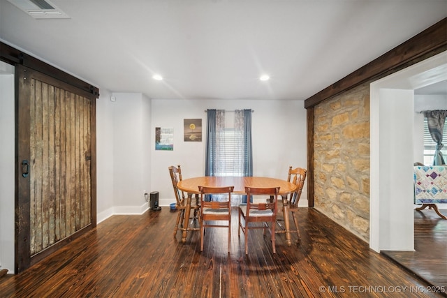 dining space with baseboards, a barn door, visible vents, and wood finished floors