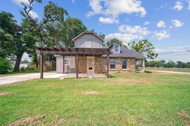 view of front of home with stone siding, a front lawn, board and batten siding, and a patio