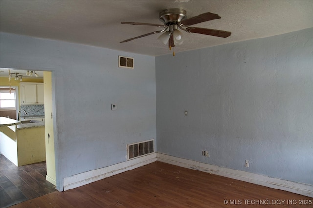 spare room with ceiling fan, visible vents, a sink, and wood finished floors