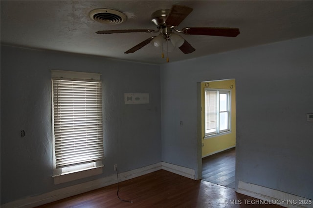 unfurnished room featuring a ceiling fan, visible vents, baseboards, and wood finished floors