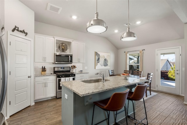 kitchen featuring stainless steel appliances, visible vents, backsplash, white cabinets, and a sink