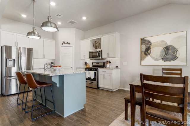 kitchen with a kitchen island with sink, stainless steel appliances, visible vents, and white cabinetry