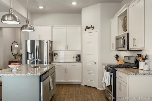 kitchen with appliances with stainless steel finishes, dark wood-type flooring, decorative light fixtures, white cabinetry, and a sink