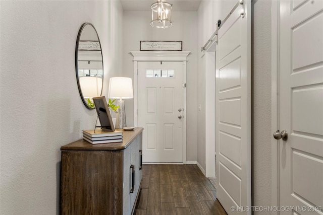 entryway featuring dark wood-type flooring, baseboards, and a barn door