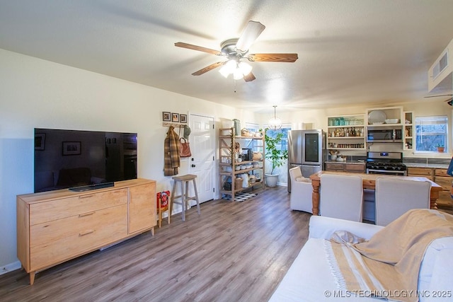 living area featuring ceiling fan with notable chandelier, visible vents, and wood finished floors