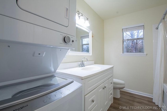 bathroom with stacked washer / dryer, toilet, a shower with curtain, wood finished floors, and vanity