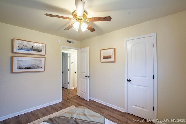 unfurnished bedroom with a ceiling fan, visible vents, baseboards, and wood finished floors