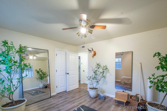 sitting room featuring visible vents, wood finished floors, a ceiling fan, and baseboards