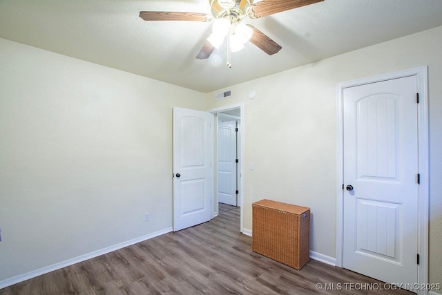 unfurnished bedroom with visible vents, ceiling fan, baseboards, and wood finished floors