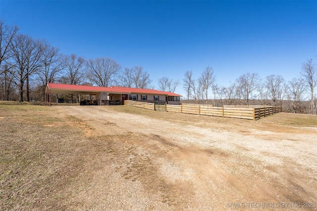 exterior space with a carport, dirt driveway, an exterior structure, and an outbuilding