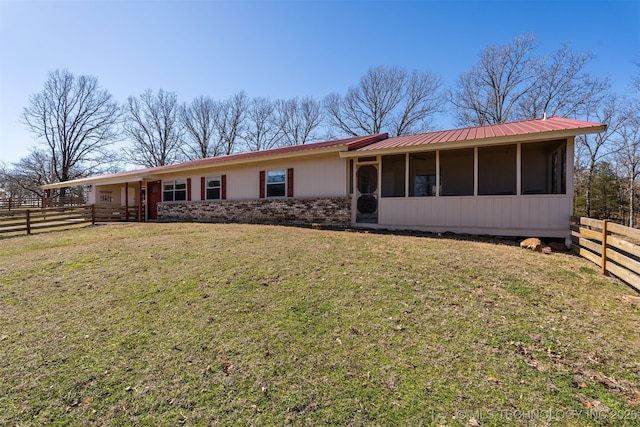 ranch-style house with brick siding, a front yard, a sunroom, fence, and metal roof