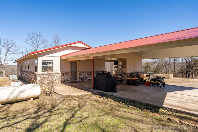 back of house with metal roof and a carport