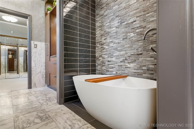 bathroom with tile walls, a freestanding tub, and marble finish floor