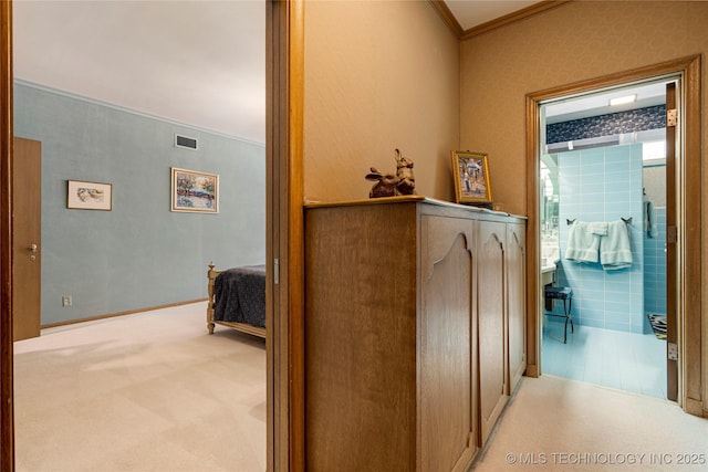 hallway with carpet flooring, visible vents, and ornamental molding