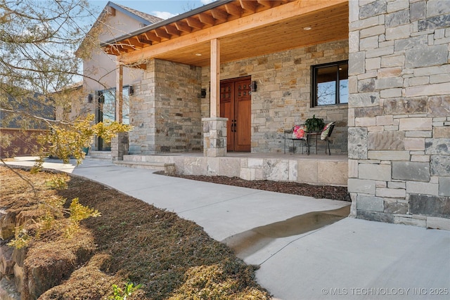 property entrance featuring stone siding and covered porch