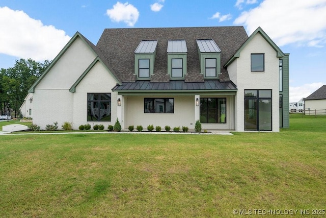 modern farmhouse featuring a front yard, a standing seam roof, and brick siding