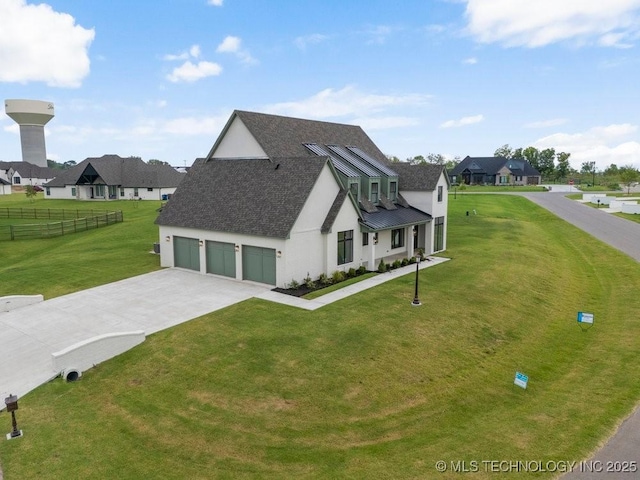 view of front of property featuring metal roof, fence, driveway, stucco siding, and a front lawn