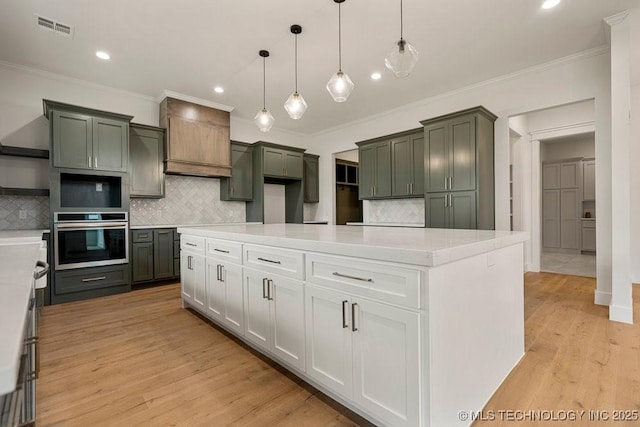 kitchen with tasteful backsplash, visible vents, crown molding, light wood-style floors, and pendant lighting