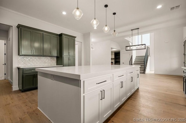 kitchen featuring light wood-style flooring, visible vents, hanging light fixtures, backsplash, and crown molding