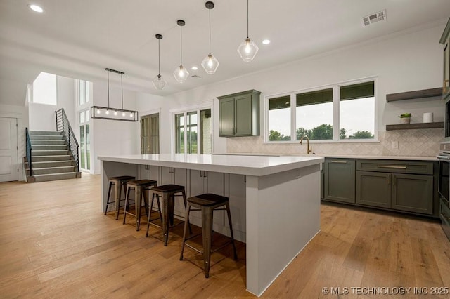 kitchen with light wood-type flooring, a center island, visible vents, and backsplash