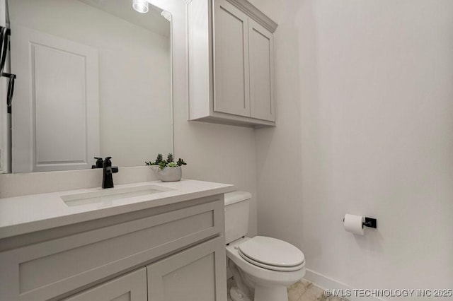 half bathroom with baseboards, vanity, and toilet