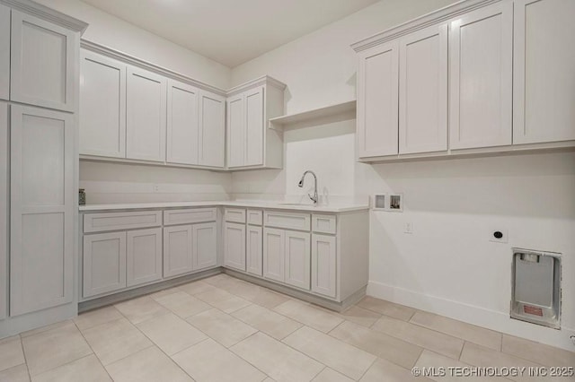 clothes washing area featuring washer hookup, cabinet space, hookup for an electric dryer, a sink, and baseboards