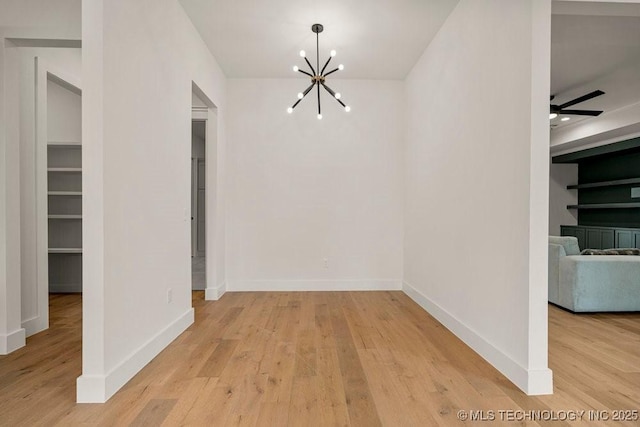 unfurnished dining area featuring light wood finished floors, baseboards, and ceiling fan with notable chandelier