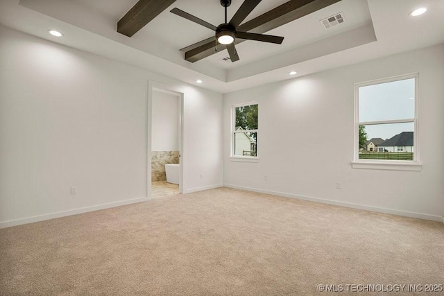 unfurnished room featuring a tray ceiling, visible vents, and light carpet