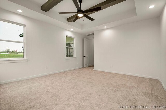 spare room featuring light carpet, recessed lighting, a raised ceiling, and baseboards